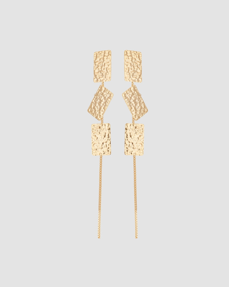 brinco comprido martelado dourado Papoula, semijoia banhada a ouro 18k com 3 peças marteladas, 9cm de comprimento, corrente fina delicada, acabamento polido brilhante, antialérgico para orelha furada, fotografado em fundo cinza neutro
