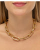 colar dourado de elos grossos, semijoia da coleção correntaria Papoula, em metal polido com brilho intenso, usado no pescoço em foto de close-up com fundo neutro