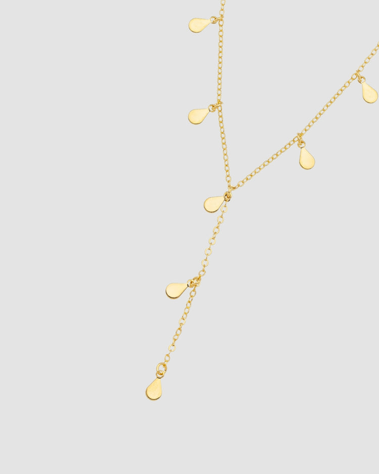 colar dourado Papoula em formato Y da coleção Lluvia, semijoia banhada a ouro 18k com gotas e comprimento de 35 cm mais 10 cm de extensor, perna do Y de 6 cm, fotografado em fundo claro com luz suave destacando brilho, caimento delicado e acabamento premium