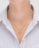 colar estrela de davi dourado Papoula sendo usado por modelo, semijoia banhada a ouro 18k com pendente estrela de 1,8cm em corrente veneziana de 45cm, zircônias brilhantes, modelo usando camisa branca com listras azuis, estilo editorial premium, fundo neutro cinza, fotografia de produto para e-commerce