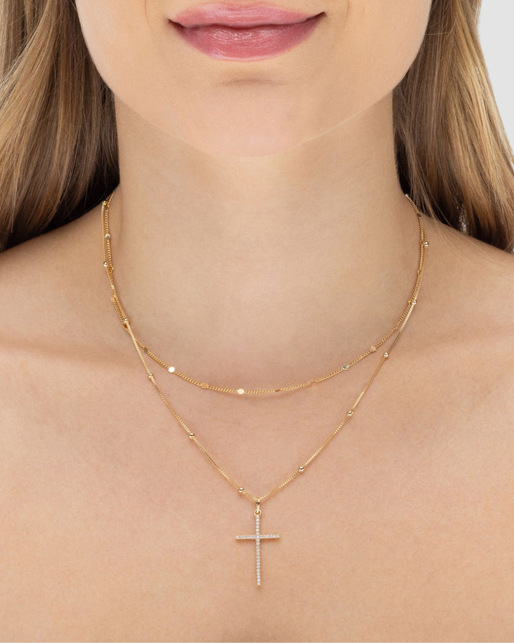 Colar duplo feminino banhado a ouro 18k com corrente satélite e pingente crucifixo cravejado de microzircônias — semijoia religiosa Papoula