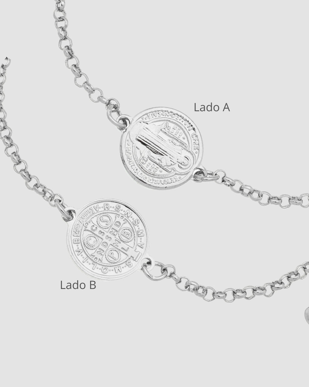 Detalhe frente e verso da medalha São Bento prateada em pulseira semijoia religiosa feminina Papoula