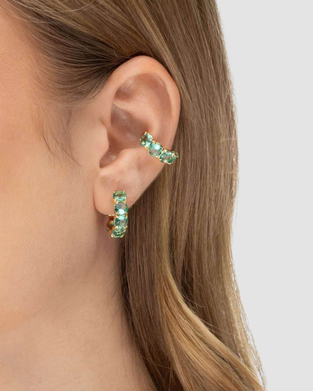 Modelo usando brinco argola cravejada zircônia esmeralda banhado a ouro combinado com piercing fake — acessório feminino Papoula