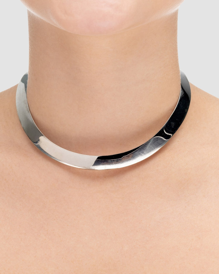 choker de aro duro prateado Papoula, semijoia com banda grossa de 1cm de espessura e encaixe perfeito no colo, acabamento polido, fotografado no pescoço