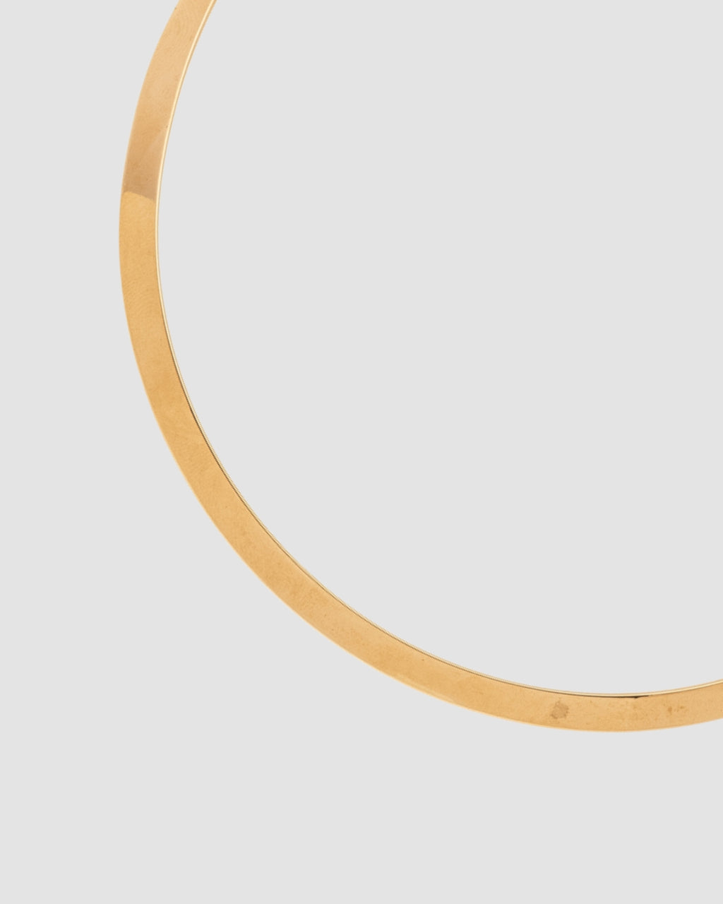 choker de aro duro dourado Papoula, semijoia com encaixe perfeito no colo, aro fino de 0,5 cm de espessura e acabamento polido, fotografado em fundo cinza neutro