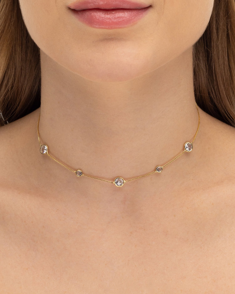 Modelo usando colar choker com zircônias cravejadas banhado a ouro no pescoço — acessório feminino Papoula