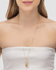 Modelo usando colar patuá longo banhado a ouro 18k com medalhas religiosas crucifixo e strass — semijoia feminina Papoula