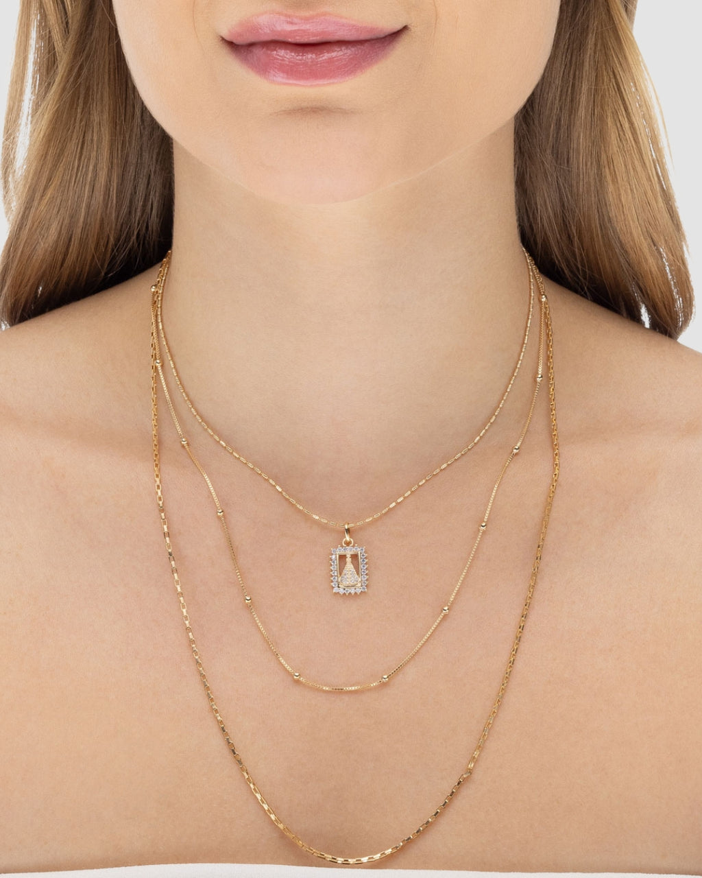 Modelo usando colar triplo feminino banhado a ouro com pingente Nossa Senhora Aparecida microzircônias — semijoia religiosa Papoula