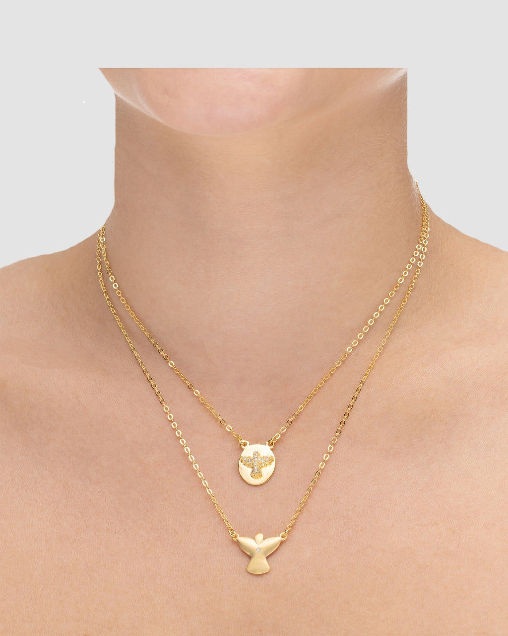 colar anjinho duplo dourado Papoula, semijoia banhada a ouro 18k com duas correntes em camadas, anjinho estilizado zirconia 40cm + 10cm extensão e anjinho minimalista 42cm, acabamento polido, fotografado no pescoço