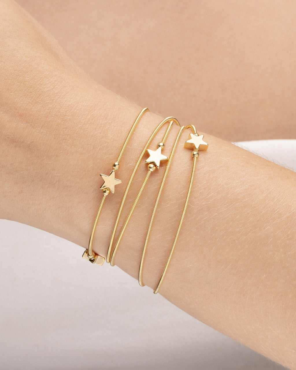 pulseira  corda de violão com 5 estrelas dourada Papoula, semijoia banhada a ouro 18k, 81cm versátil 6 voltas pulso ou 2 voltas pescoço, design inspirado cordas violão, acabamento polido, fotografado no pulso