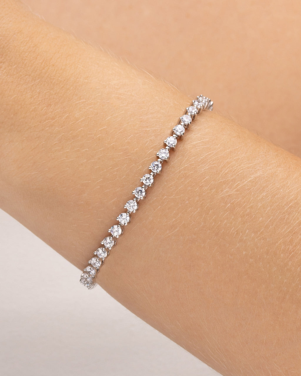 pulseira riviera prateada com zircônia Papoula, semijoia com zircônias brilhantes, 17cm de comprimento, fecho de segurança em caixa, acabamento polido brilhante, antialérgica, fotografada no pulso